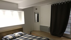 Un dormitorio con una cama, una ventana con persianas, un radiador y una puerta.