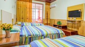 Habitación de hotel con tres camas, un televisor y una pared de madera.