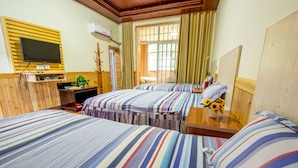 Habitación de hotel con dos camas, televisión, escritorio y ventana con cortinas.