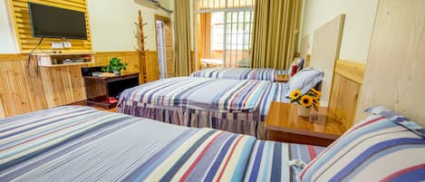 A hotel room with two beds, a TV, a desk, and a window with curtains.