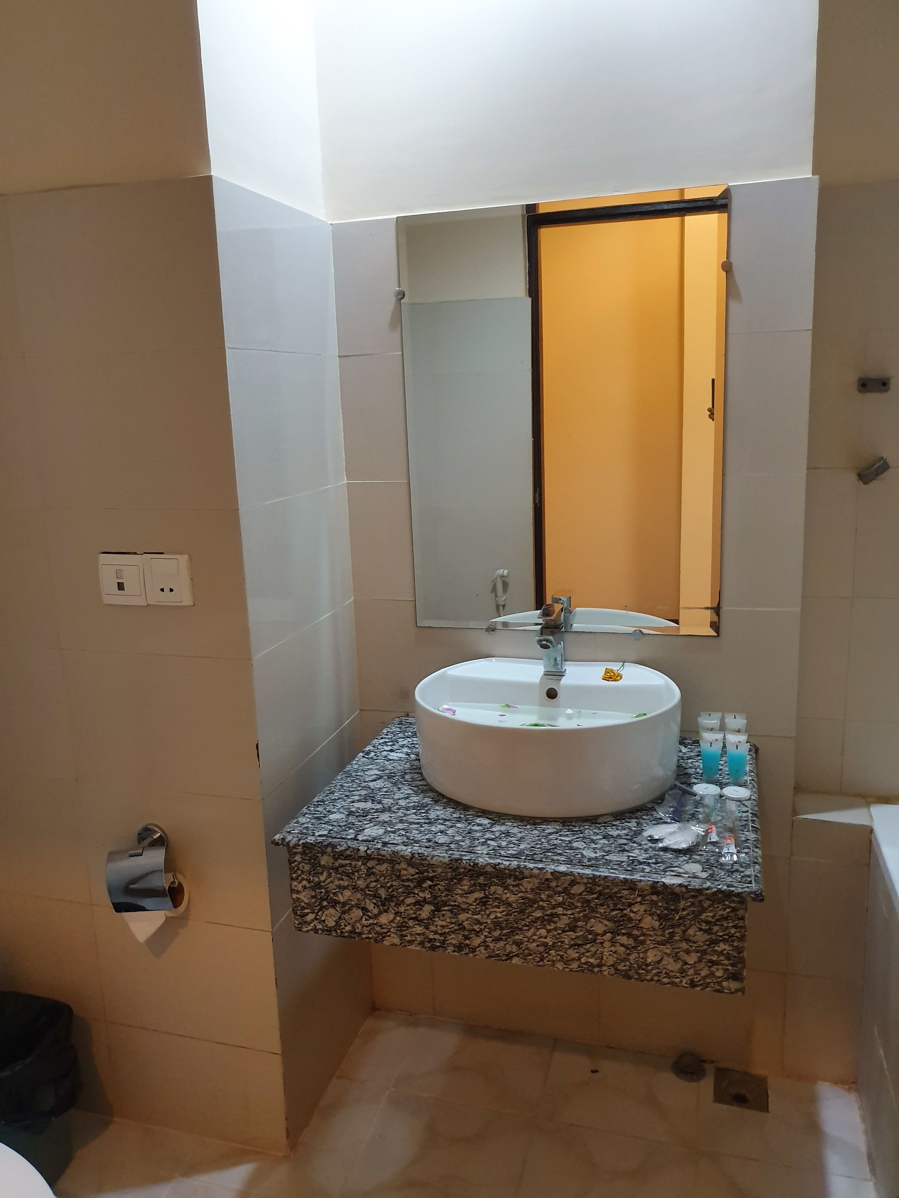 Ein Badezimmer mit einem runden Waschbecken, einem Spiegel und einem gefliesten Boden.