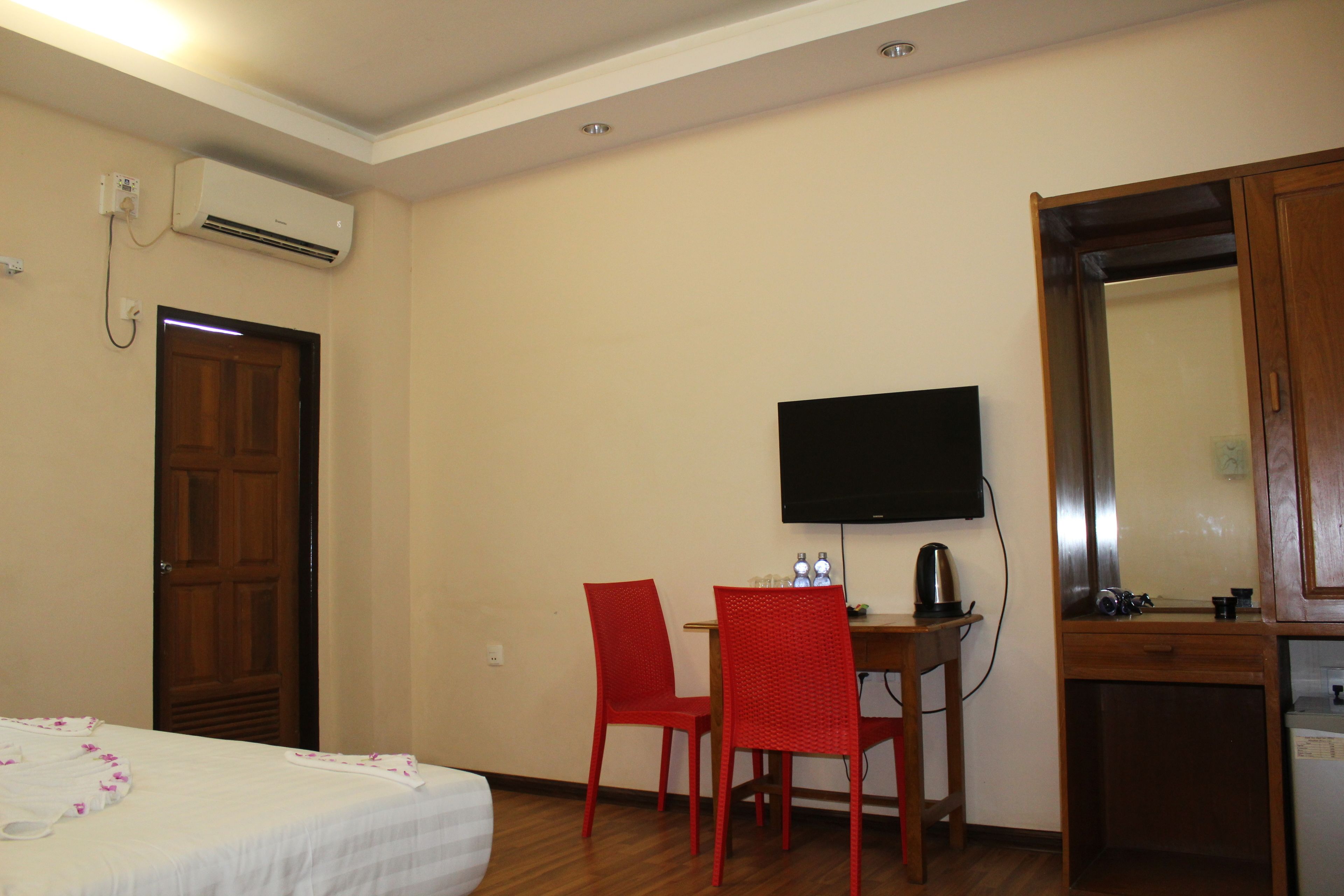 Une chambre d’hôtel équipée d’un lit, d’un bureau avec une chaise, d’une télévision et d’un appareil de climatisation.