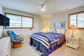 A bedroom with a bed, a chair, a nightstand, and a ceiling fan. - Beachfront Whidbey Island Home + Apartment! (Langley)