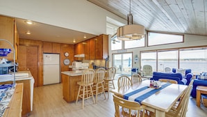 A spacious kitchen with wooden cabinets, a central island, and a dining area with wooden chairs and a table. - Beachfront Whidbey Island Home + Apartment! (Langley)