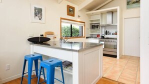 Una cucina moderna con isola centrale, sgabelli da bar, microonde, forno e un'ampia finestra.