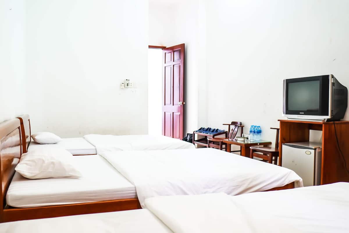 A hotel room with two beds, a television, a small table with a water dispenser, and a door.