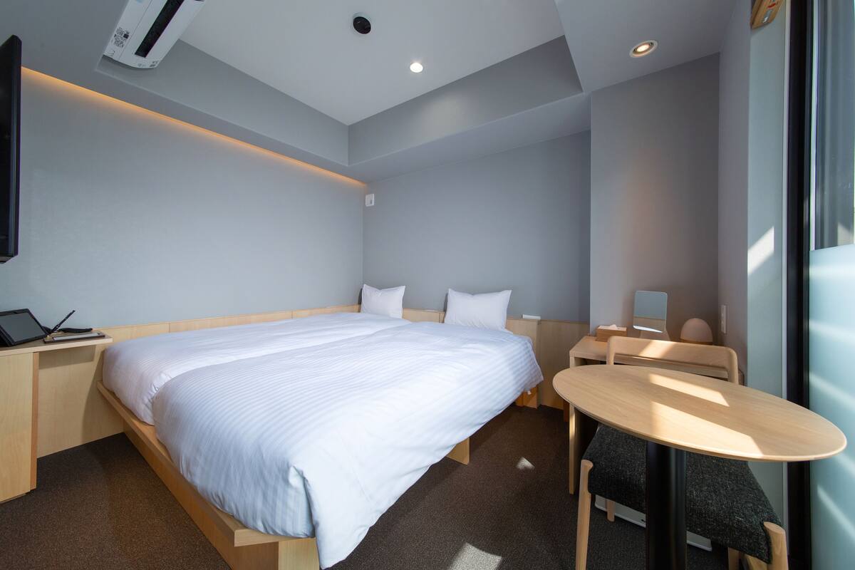 Ein modernes Hotelzimmer mit einem großen Bett, einem Schreibtisch mit einem Laptop, einem runden Tisch und einem Stuhl.