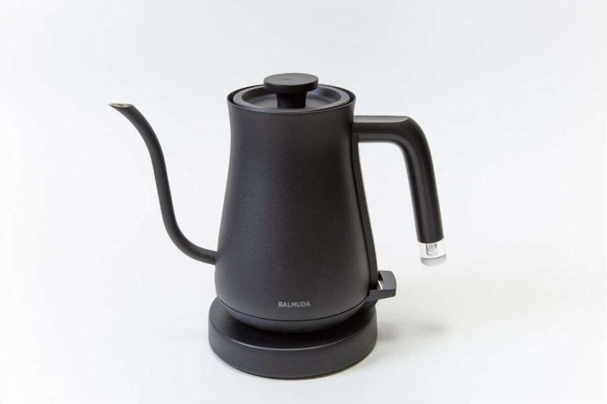 A black coffee maker with a spout and handle, placed on a white surface.