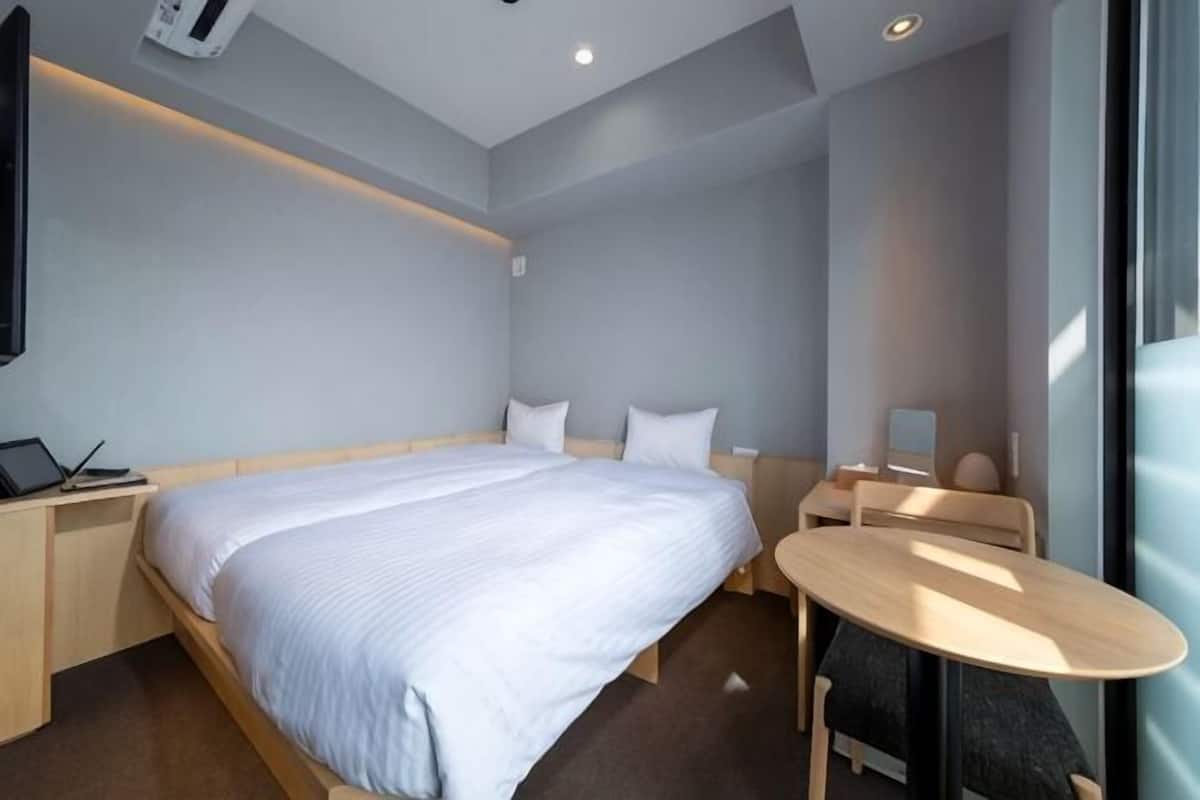 Ein modernes Hotelzimmer mit einem großen Bett, einem Nachttisch und einem kleinen runden Tisch.