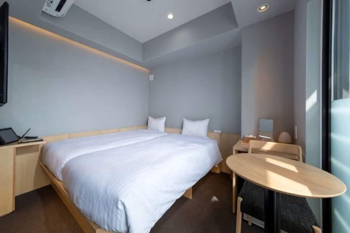 Moderni hotellihuone, jossa on suuri sänky, yöpöytä ja pieni pyöreä pöytä.