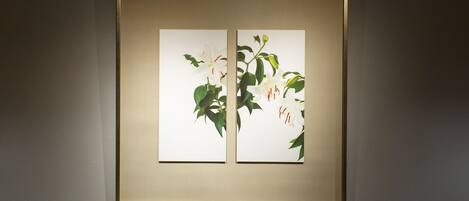 A framed artwork with two panels of white flowers and green leaves on a wall.