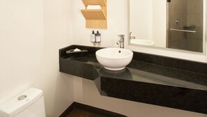A modern bathroom with a white toilet, a black sink, and a large mirror above the sink. - Gamma Querétaro (Querétaro)