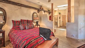 Un dormitorio con una cama grande, un ventilador de techo, una viga de madera y un espejo.