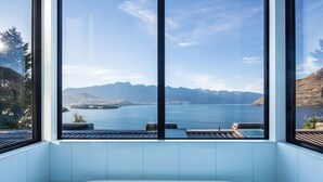 A modern bathroom with a large bathtub, a view of a lake, and mountains in the background. - Bellbrae by MajorDomo | Stylish 5-Bedroom Villa with Sauna, Spa Pool & Sweeping Lake Wakatipu Views (Queenstown)