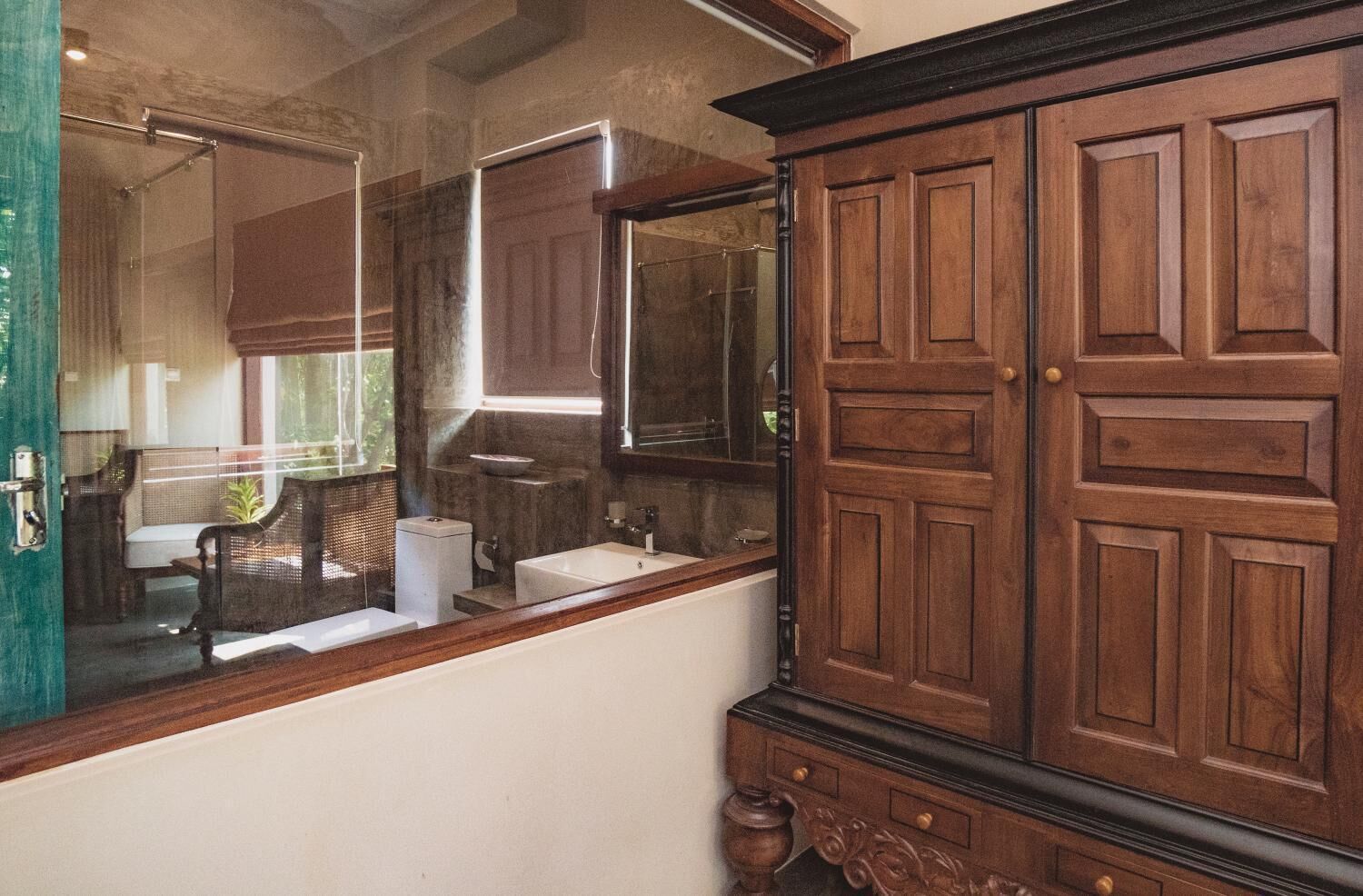 A bathroom with a wooden vanity, a large mirror, and a window.