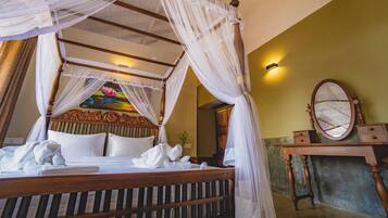 A four-poster bed with a canopy, a wooden headboard, and a bedside table with a mirror.