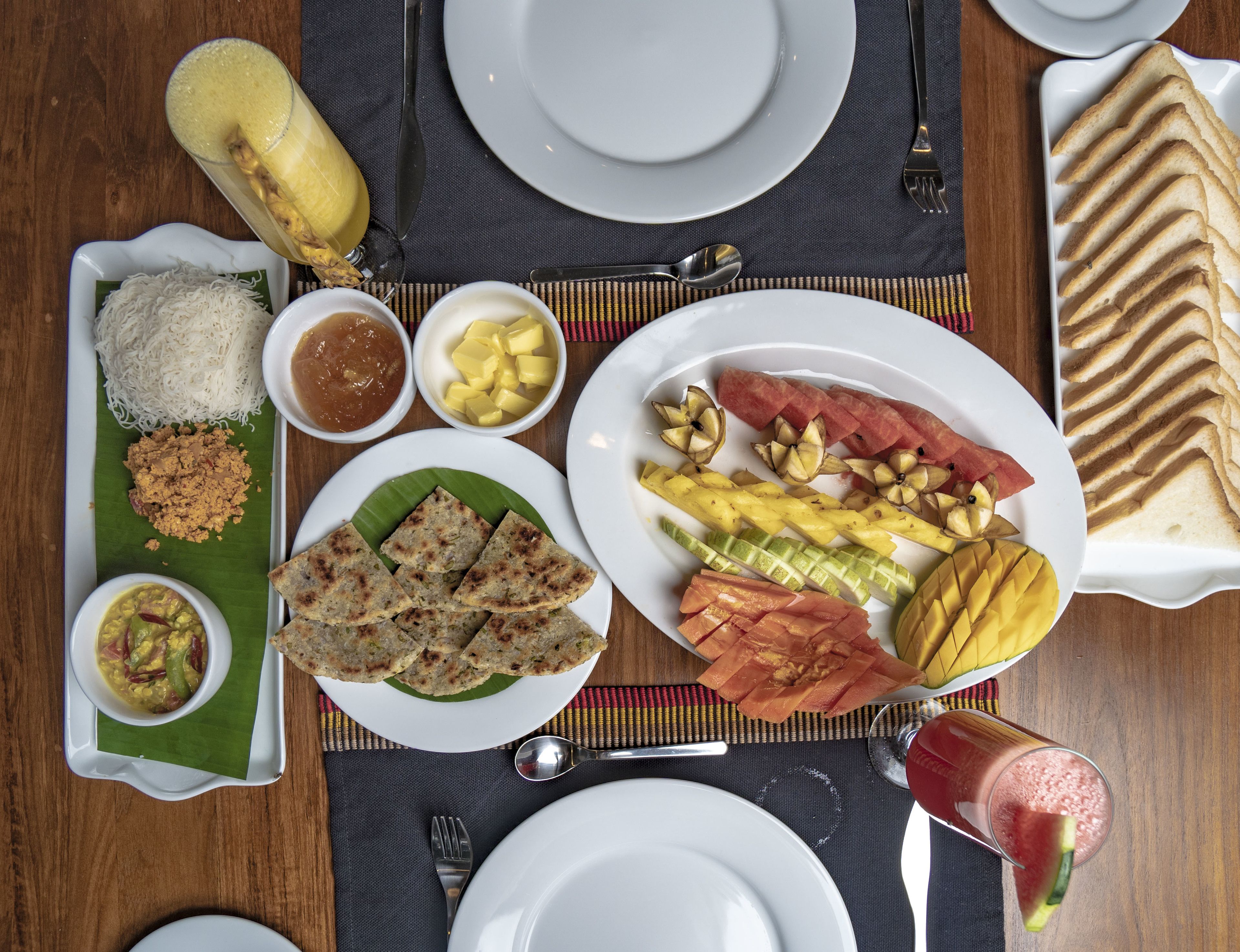 Una mesa dispuesta con varios platos, incluyendo arroz, pan, frutas y un vaso de bebida.