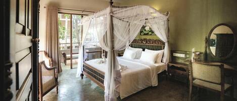 A four-poster canopy bed with white bedding, a wooden headboard, and a mirror on the wall.