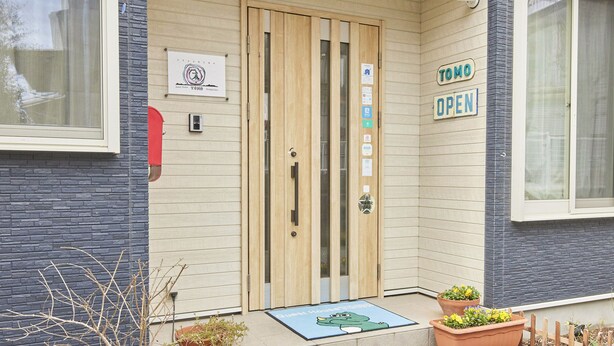 Una puerta de madera con un letrero que dice "TOMO OPEN" y un cartelito encima.