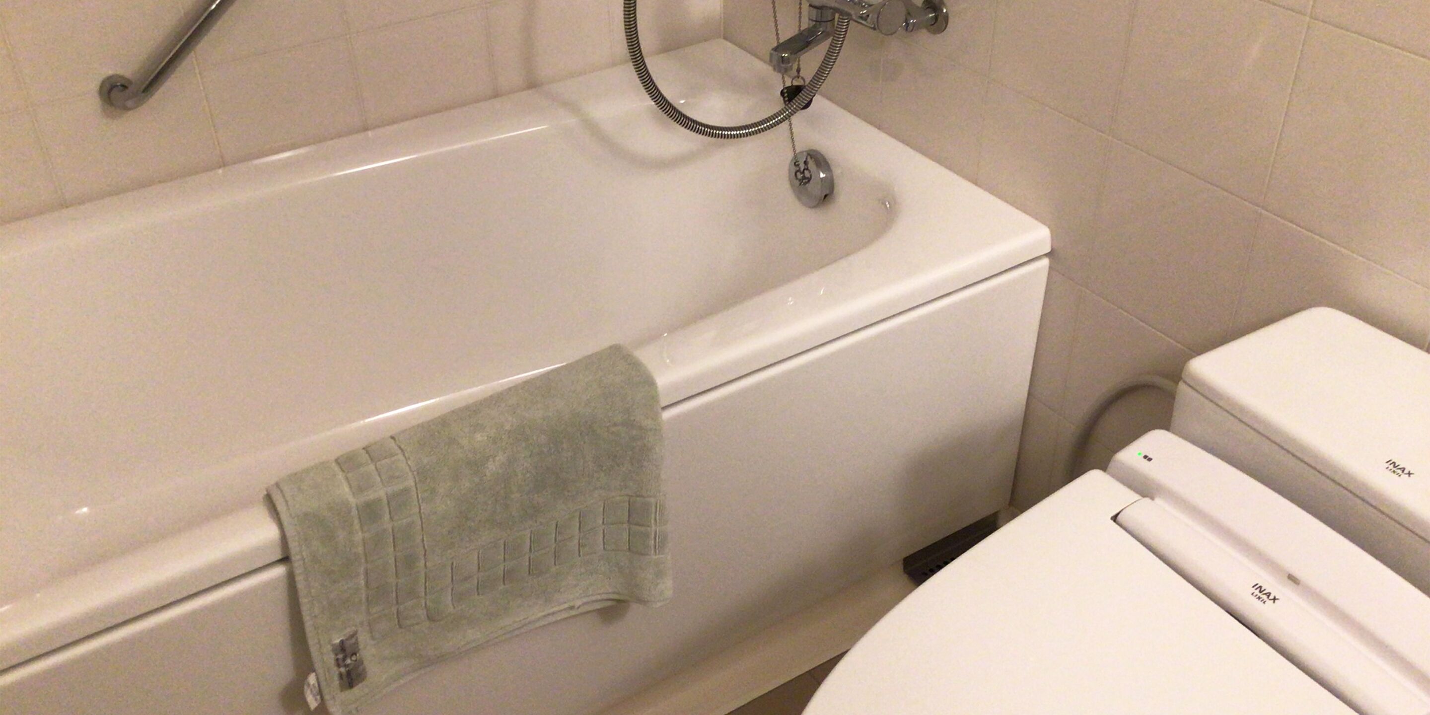 Un baño con una bañera blanca, una toalla colgando en la pared y un inodoro blanco.
