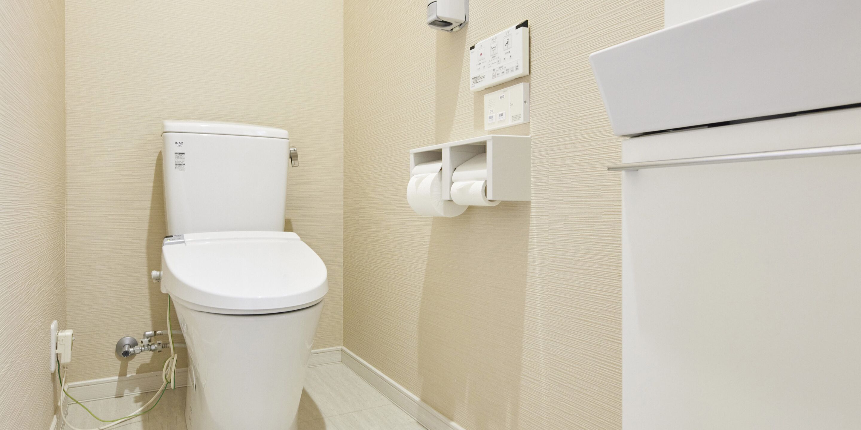 Une salle de bain équipée de toilettes, d’un distributeur d’essuie-tout et d’une prise électrique murale.