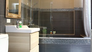 Ein modernes Badezimmer mit einem großen Spiegel, einer Dusche und einer Toilette.