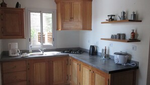 A kitchen with wooden cabinets, a gas stove, a coffee maker, and a toaster.