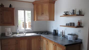 A kitchen with wooden cabinets, a gas stove, a coffee maker, and a toaster.