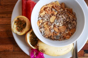 A plate with a bowl of cereal, a half-cut fruit, and a banana. - UVIVU by Jambiani Villas (Jambiani)