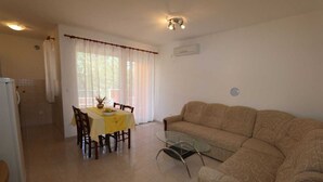 A living room with a sofa, a glass coffee table, and a dining area with a table and chairs. - Apartment Dudovic Darko nr 2 (Silo - island Krk)