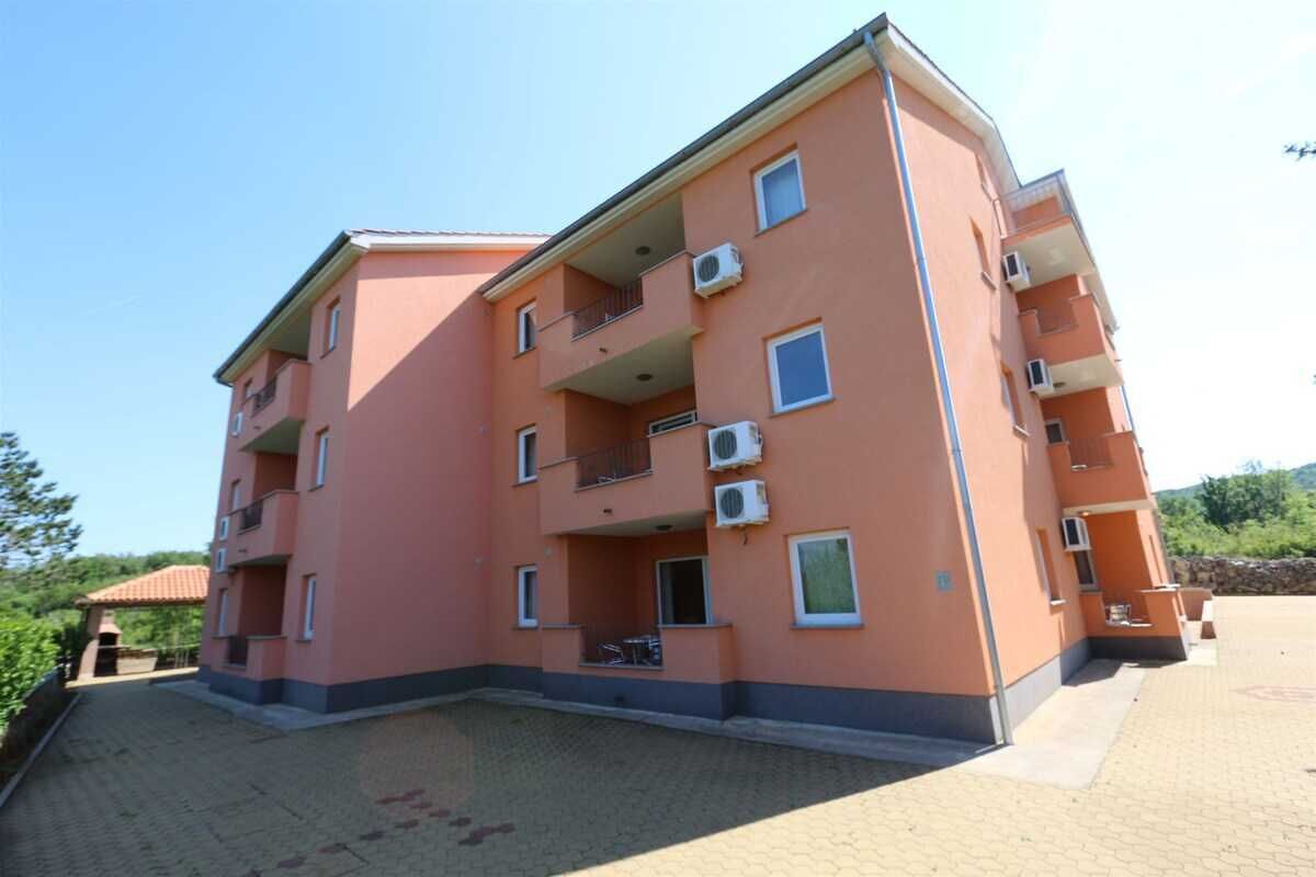 A multi-story building with balconies, air conditioning units, and a paved courtyard.