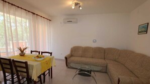 A dining area with a table and chairs, a sofa, and a glass coffee table. - Apartment Dudovic Darko nr 2 (Silo - island Krk)