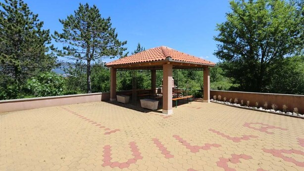 A gazebo with a tiled roof, surrounded by a paved area with a geometric pattern. - Apartment Dudovic Darko nr 2 (Silo - island Krk)