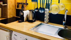 Una cocina compacta con lavadora, un lavabo y varios utensilios colgados en la pared.