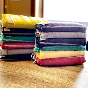 A stack of folded towels in various colors on a wooden surface.