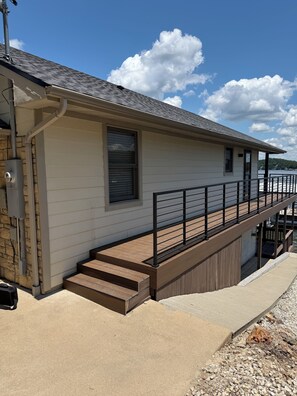 Une maison dotée d’une terrasse en bois, de fondations en pierre et offrant une vue sur l’eau.