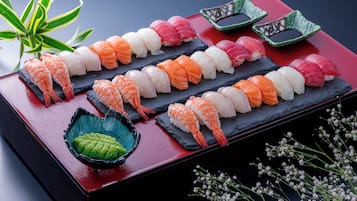 A variety of sushi arranged on a black slate plate with a red background.