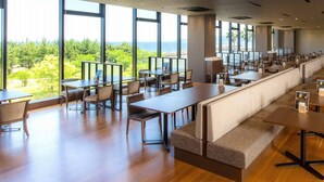 A spacious restaurant with high ceilings and large windows offering a view of the ocean. - REX HOTELBeppu (Beppu)