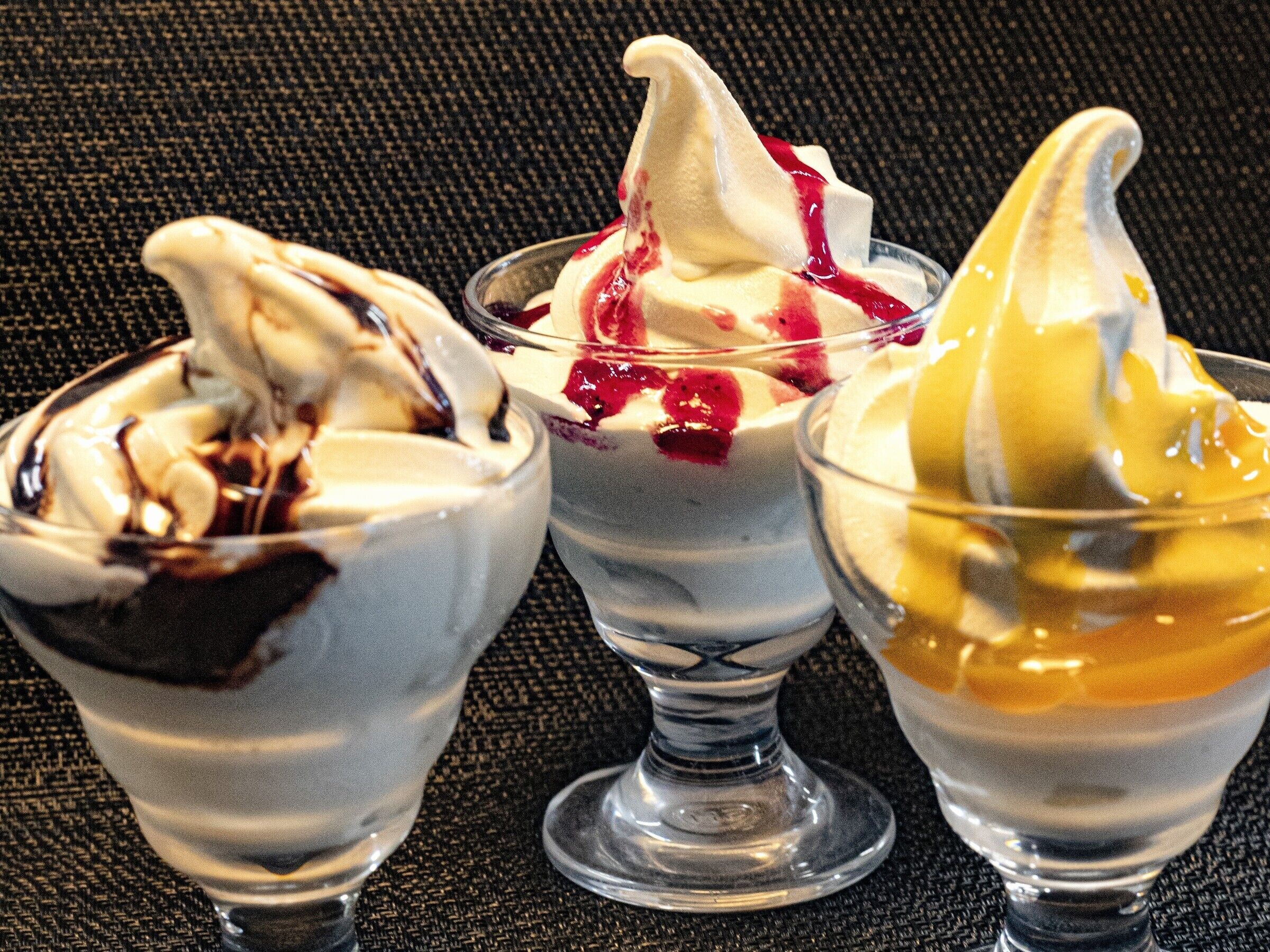 Three dessert cups with whipped cream and toppings.
