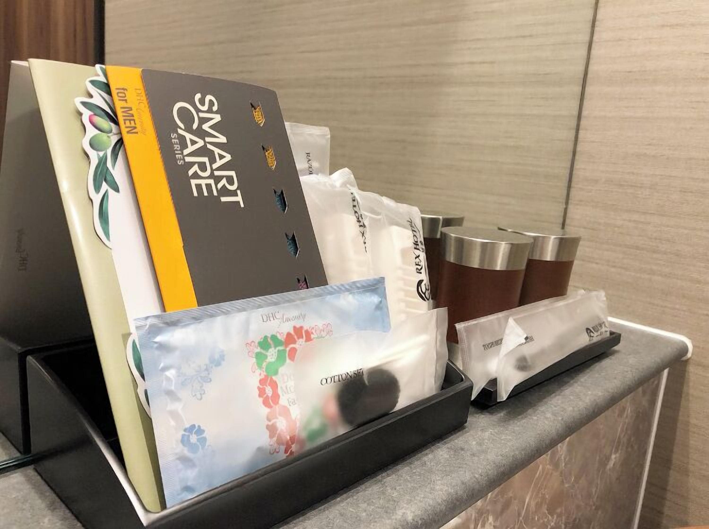 A hotel reception area with a self-service kiosk displaying amenities like toiletries and a book titled 'Smart Care for Men'.