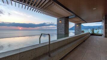 A modern outdoor pool area with a view of the sea and mountains.