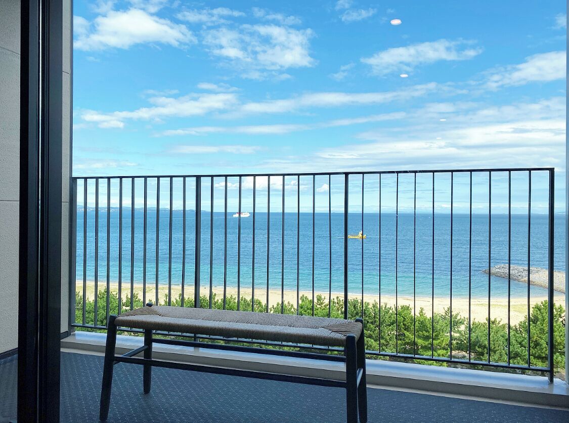 A balcony with a view of the ocean and a bench.