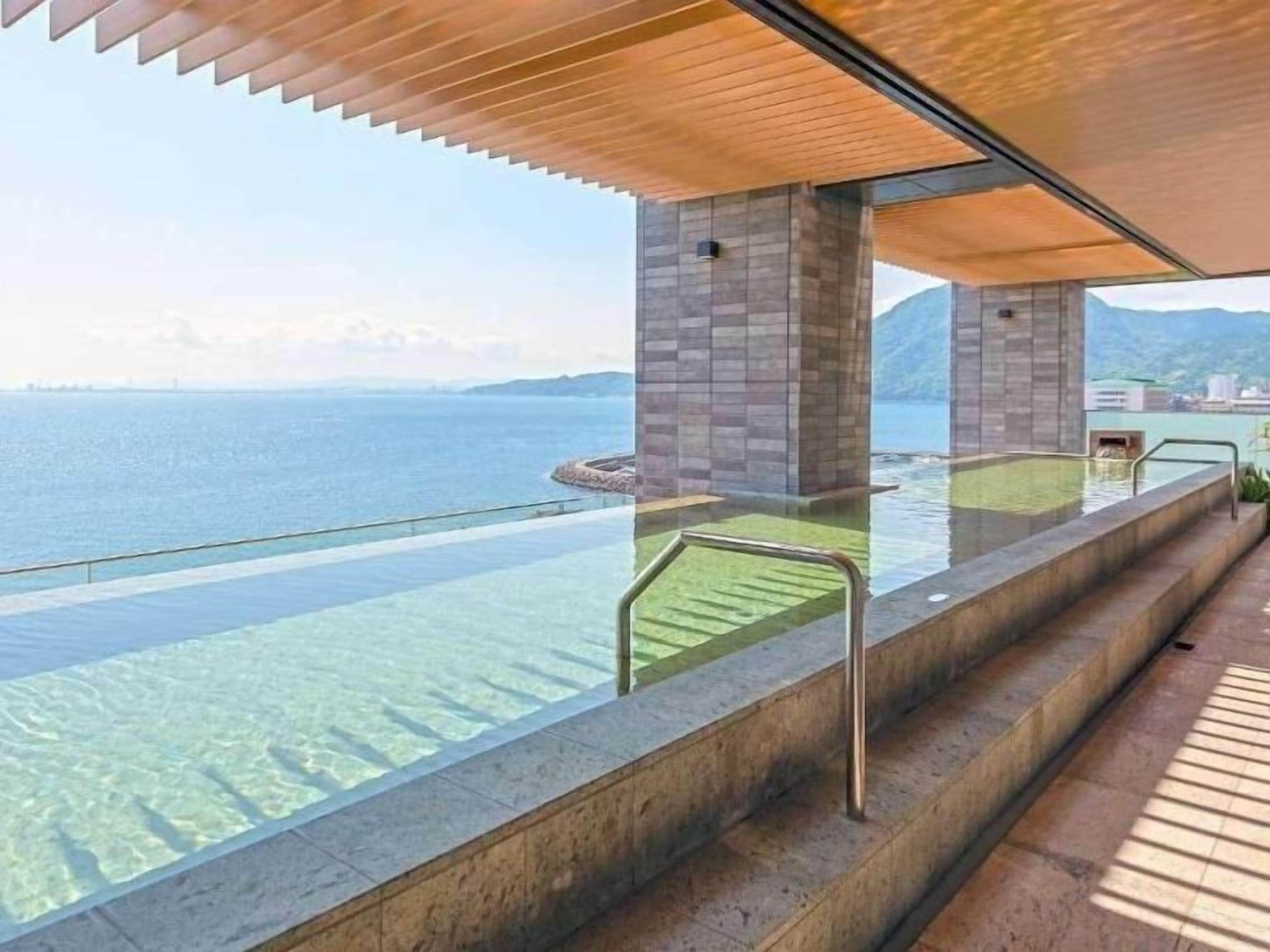Zona de piscina con agua cristalina, escalones que bajan al agua y vistas al mar.