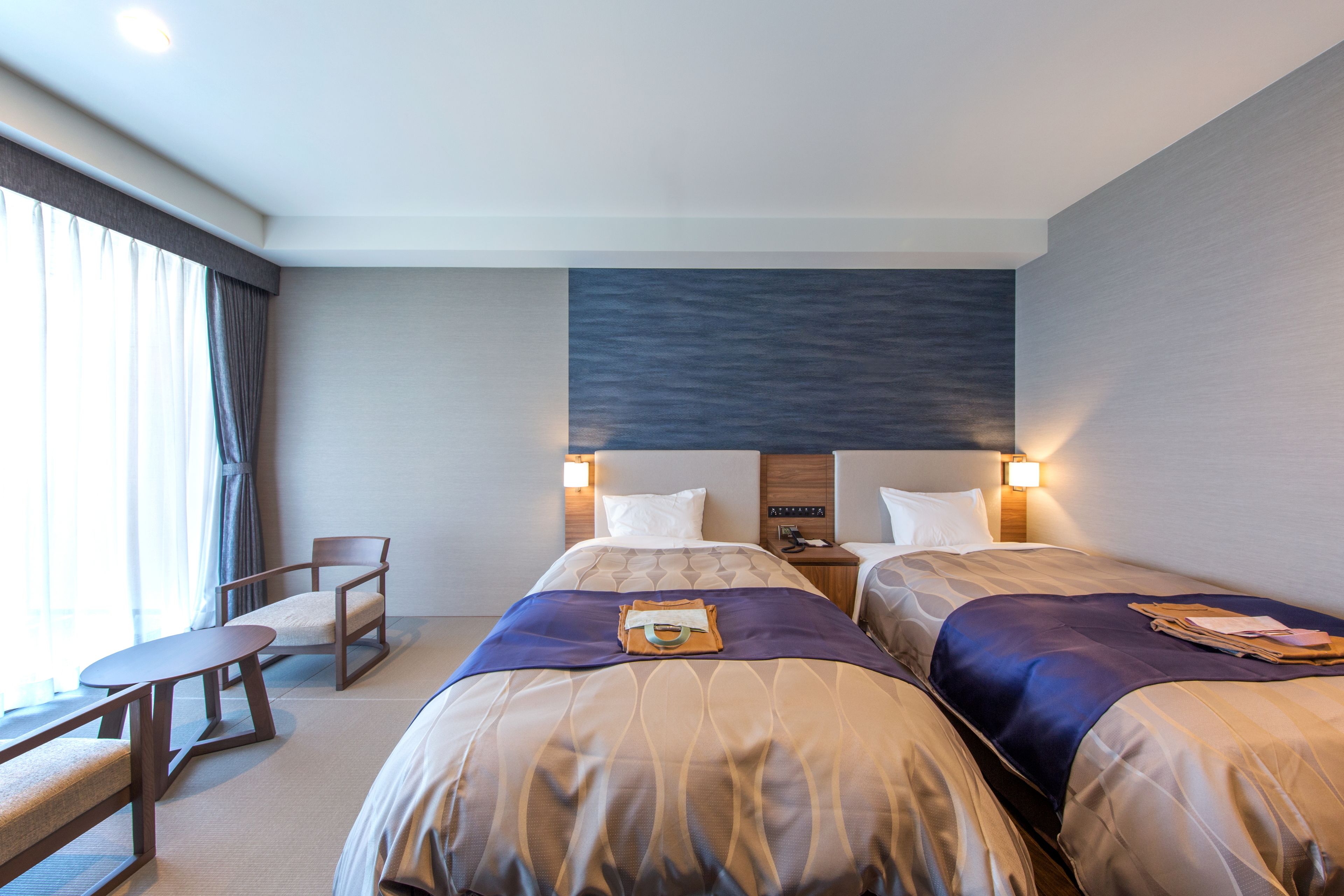A hotel room with two beds, a desk, and a chair.