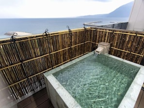 A hot tub with a bamboo fence, clear water, and a view of the sea. - REX HOTELBeppu (Beppu)