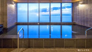 A large indoor swimming pool with a view of a body of water and a cityscape. - REX HOTELBeppu (Beppu)