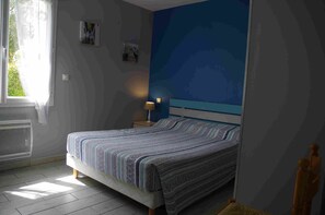 A bedroom with a bed, a nightstand, a lamp, and a window with curtains. - Charming furnished holiday rental on the Bassin d'Arcachon. (Audenge)