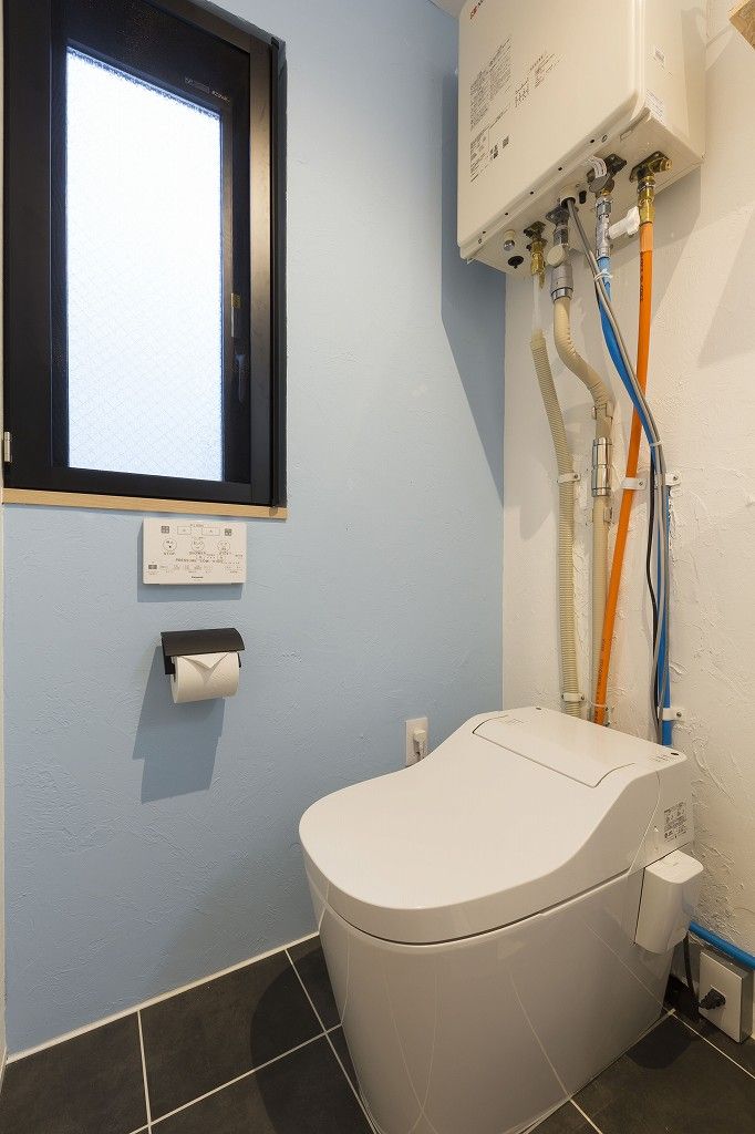 Un baño con inodoro, ventana y calentador de agua.