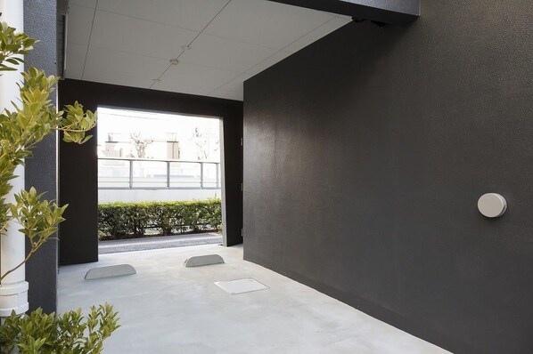 Un intérieur moderne avec un sol en béton, un mur foncé et une petite fenêtre donnant sur un balcon.