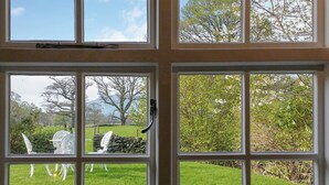 A view through a window with a view of a grassy area, a stone wall, and a tree. - 1 bedroom accommodation in Borrowdale, near Keswick (Borrowdale, near Keswick)